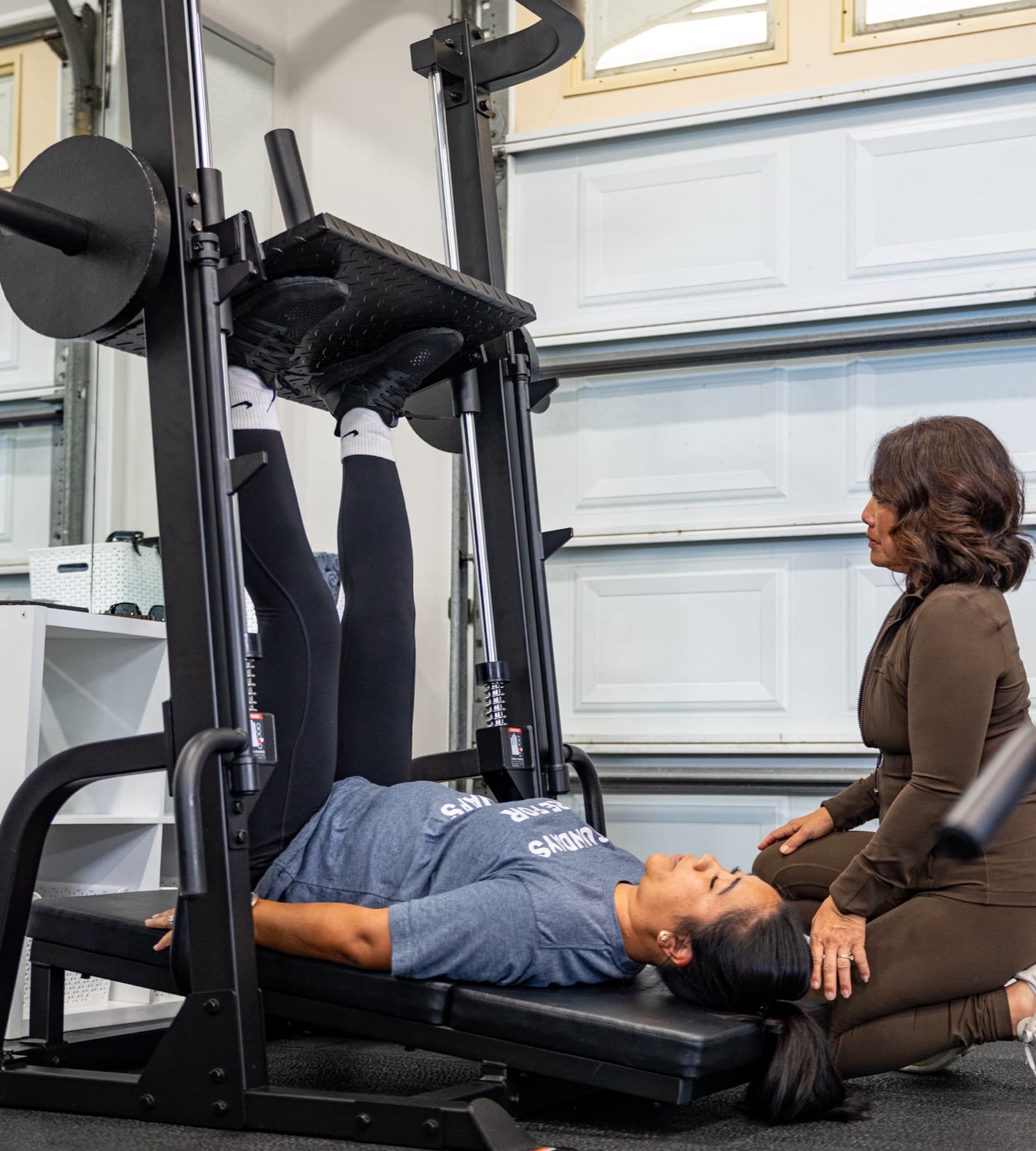 Lissa kneeling beside a member through a leg press.