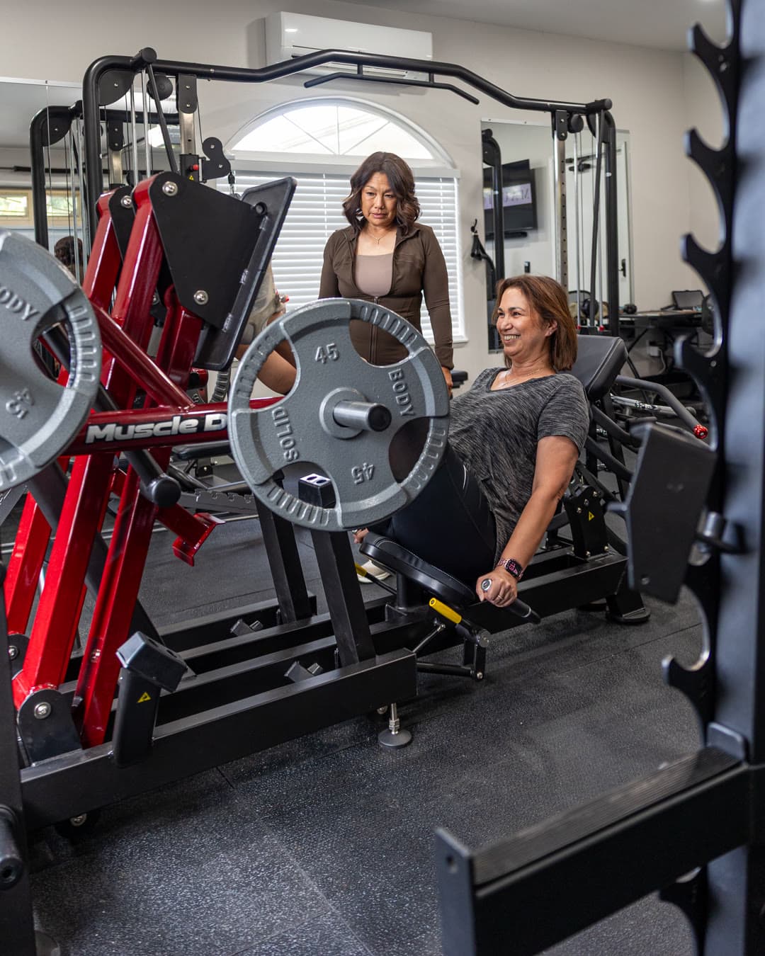 Two members training together at the leg press in the studio.